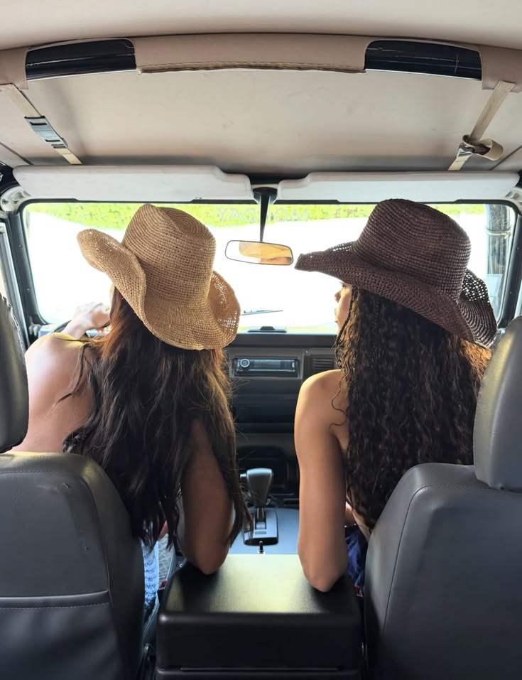 Two women in cowboy hats sitting together inside a vehicle